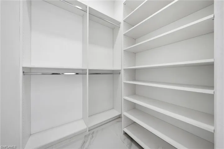 Custom closet system featuring white shelving and chrome hanging rods