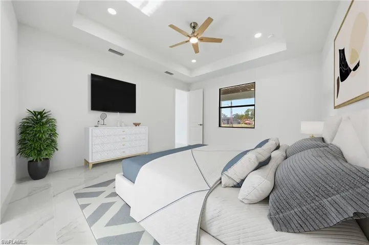 Tray ceiling with recessed lighting, ceiling fan, white walls, and large window