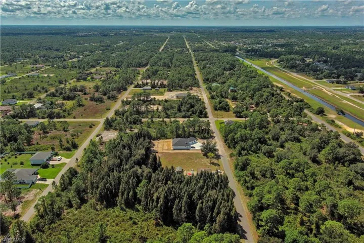 Drone / aerial view of a heavily wooded area and a nearby body of water
