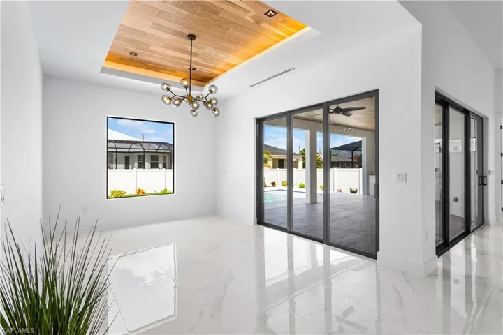 Sizeable DINING ROOM is ideal for MEMORABLE FORMAL DINING experiences, featuring ATTRACTIVE CHANDELIER, FLAT WOODEN CEILING w/ LED light track, stackable doors that open to the LANAI and BIG PICTURE WINDOW overlooking POOL AREA.