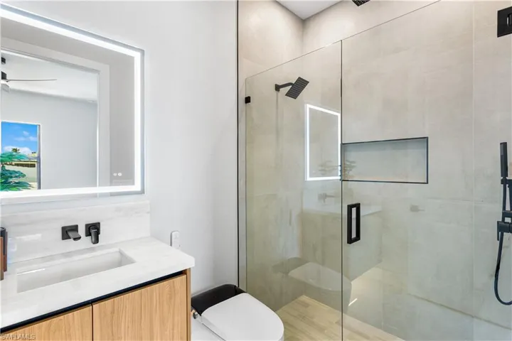 2nd ENSUITE MASTER BATHROOM with quartz countertops, custom mirror, electric toilets, tiled shower with rainfall, head, and handheld shower heads.