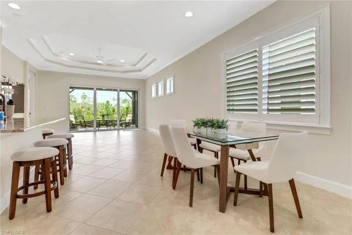 Dining room with a ceiling fan, recessed lighting, light tile patterned floors, ornamental molding, and a tray ceiling