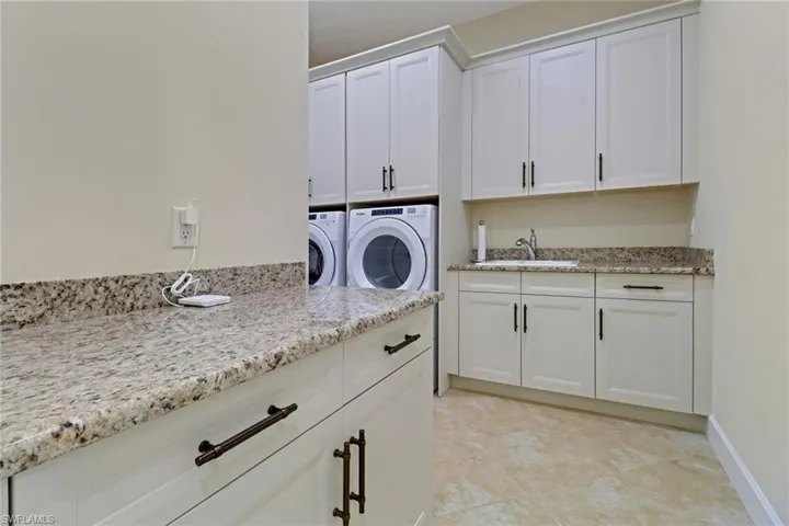 Laundry area with cabinet space, separate washer and dryer, and light tile patterned floors
