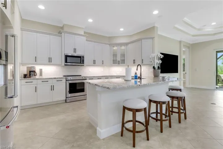 Kitchen featuring stainless steel appliances, a peninsula, backsplash, a breakfast bar area, and white cabinetry