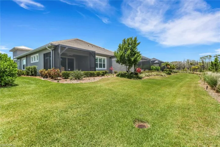 Rear view of property with a lawn, glass enclosure, and stucco siding