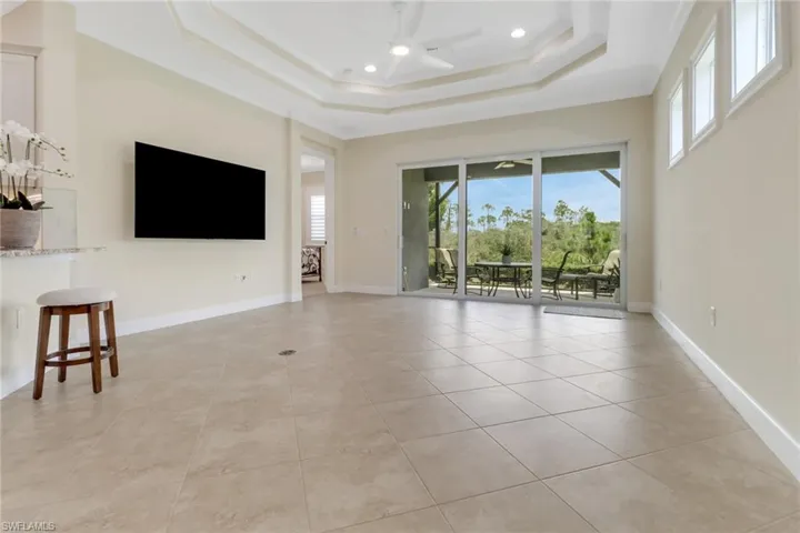 Unfurnished living room with a raised ceiling, a ceiling fan, light tile patterned floors, and recessed lighting