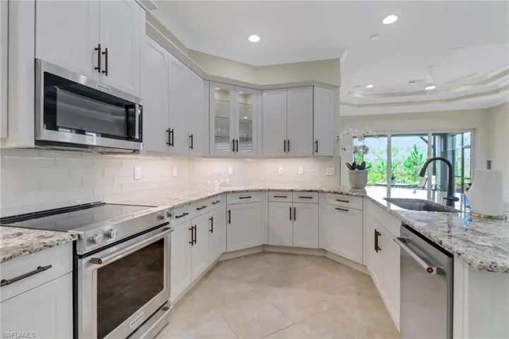 Kitchen with stainless steel appliances, a peninsula, backsplash, white cabinets, and recessed lighting