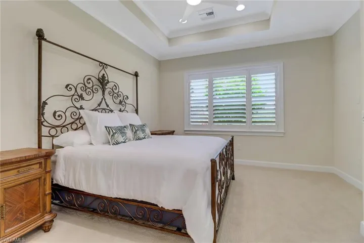 Bedroom with light colored carpet and a raised ceiling