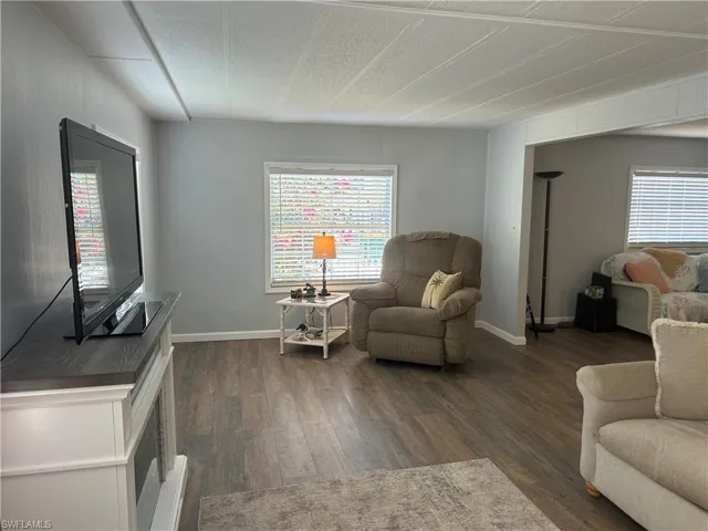 Living room with dark wood finished floors and healthy amount of natural light