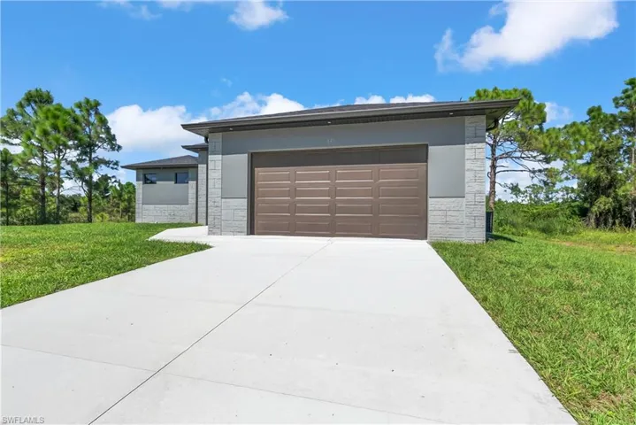 Prairie-style home with stone siding, driveway, a front yard, and stucco siding