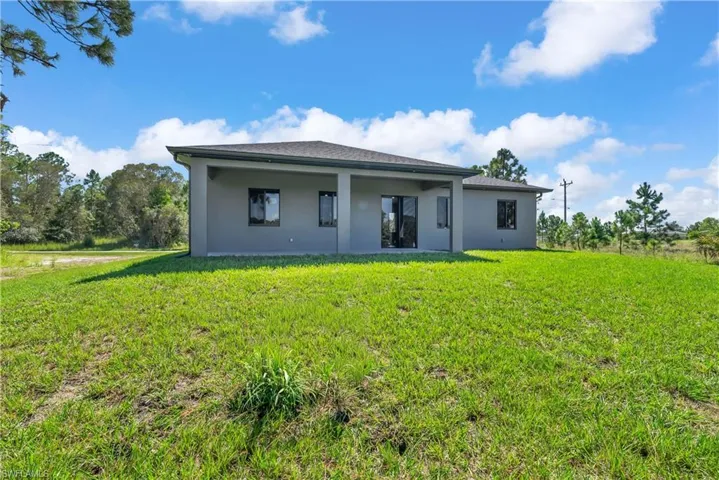 Back of property with a yard, stucco siding, and a patio area