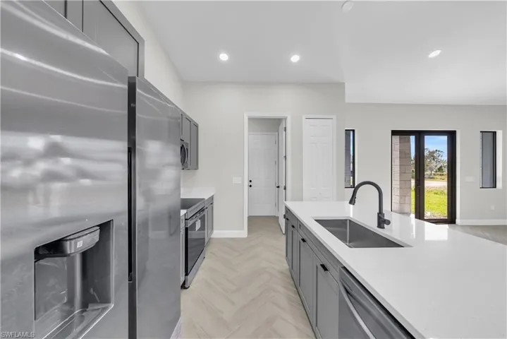 Kitchen featuring gray cabinets, recessed lighting, light stone counters, and appliances with stainless steel finishes