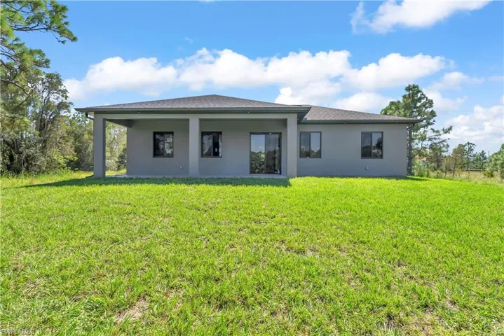 Back of property featuring stucco siding, a lawn, and a patio