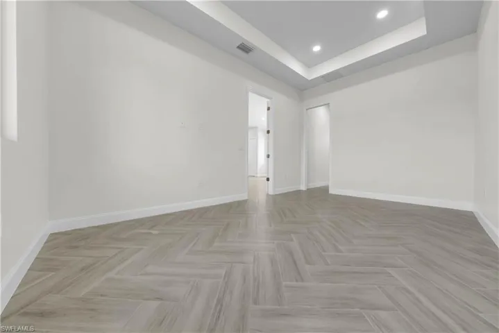 Empty room featuring a tray ceiling and recessed lighting
