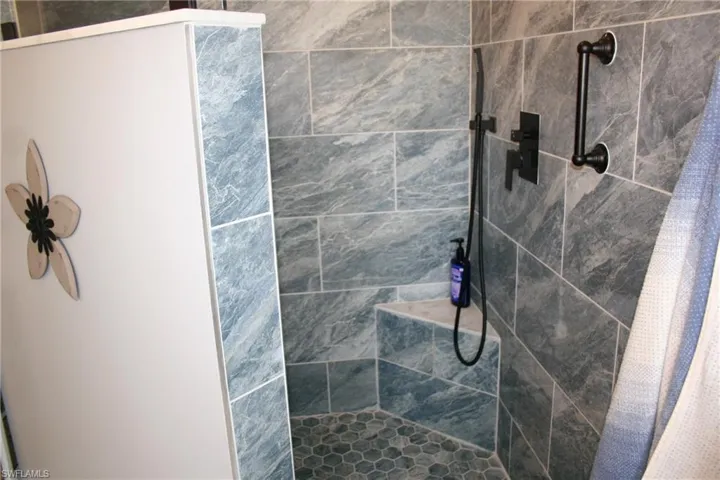 Tiled shower with a built-in bench, hexagon tile flooring, and matte black fixtures