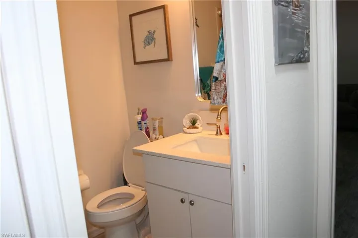 White vanity with integrated sink, brass-finish faucet, and coordinating mirror