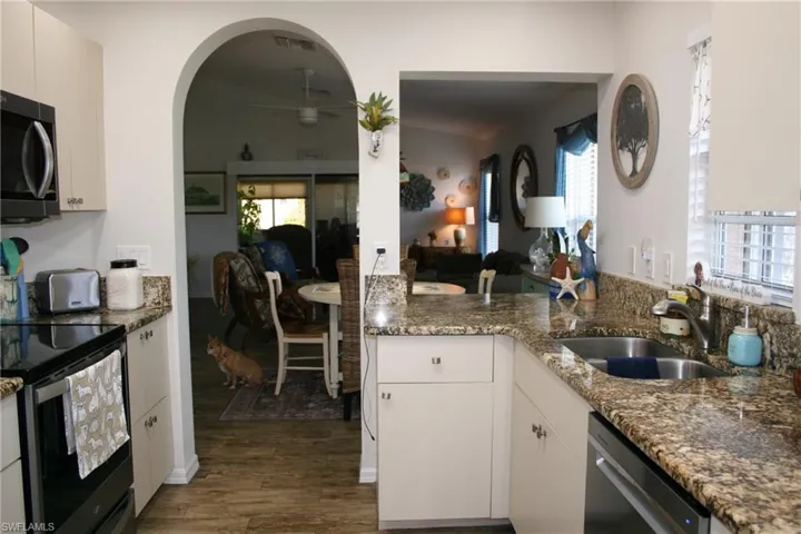 Kitchen featuring wood-finish flooring, light-toned cabinetry, granite countertops, and an integrated stainless steel sink