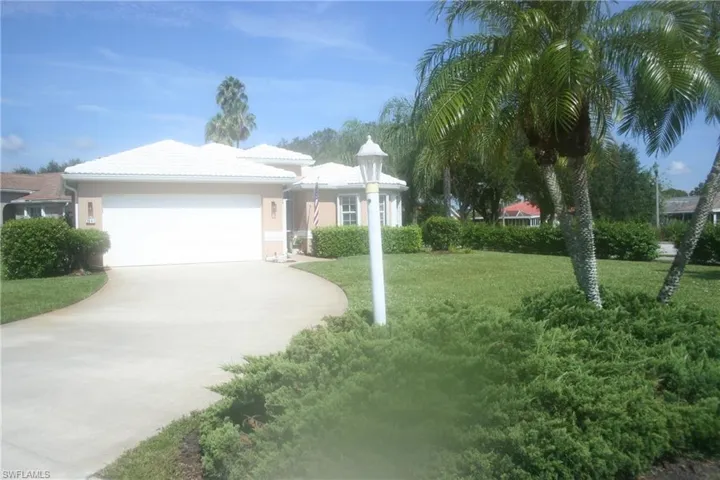 Charming single-story residence featuring a circular driveway, stucco exterior with arched architectural details, and a barrel tile roof