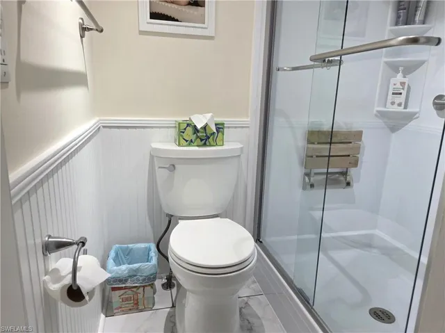 Bathroom with a wainscoted wall and a walk in shower.