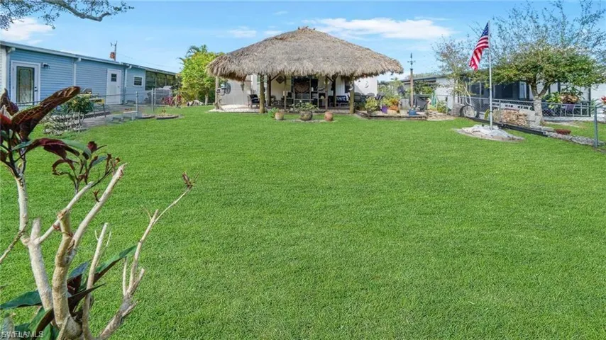 Fenced backyard featuring a custom built Tiki Hut