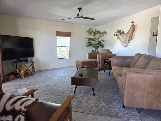 Living room with a decorative wall, wood finished floors, and ceiling fan