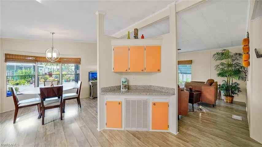 Kitchen with light wood-type flooring, suspended lighting, plenty of natural light, lofted ceiling, and light stone counters
