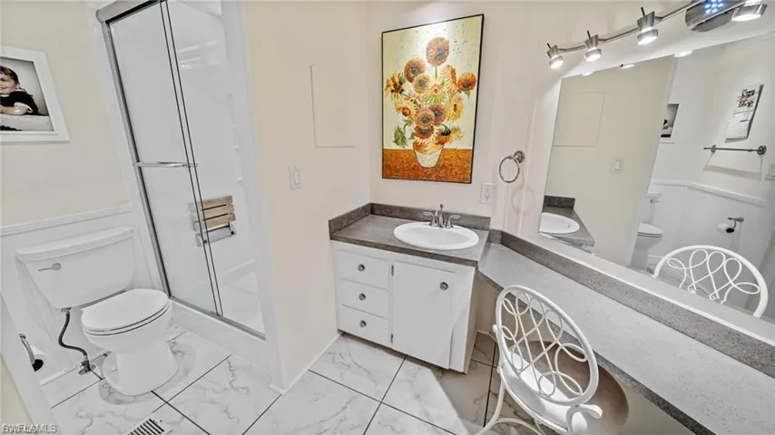 Master Bathroom with vanity, a shower stall, light marble finish floors, and a wainscoted wall