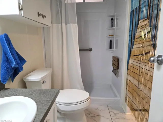 Full bath with vanity, a stall shower, and light marble finish floors