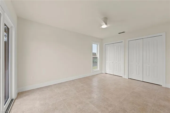 Unfurnished bedroom with multiple closets, light tile patterned flooring, baseboards, and a ceiling fan