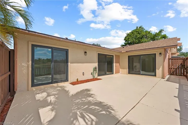 Rear view of house with stucco siding, a patio, and fence