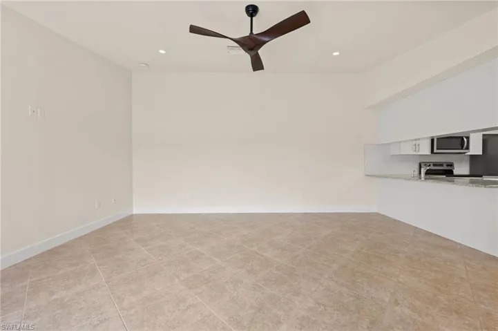Unfurnished living room featuring ceiling fan, recessed lighting, light tile patterned floors, and baseboards