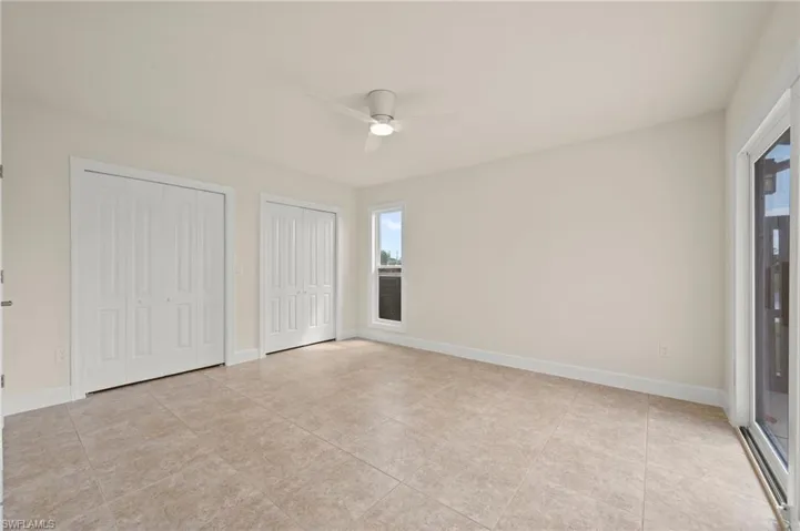 Unfurnished bedroom featuring multiple closets, light tile patterned floors, baseboards, and a ceiling fan