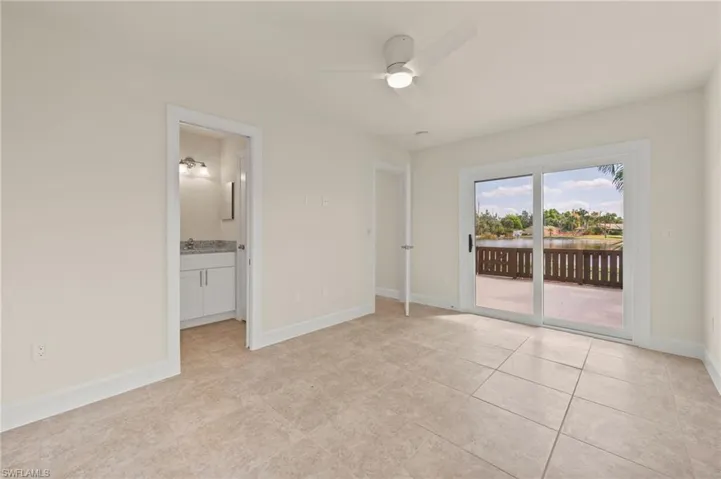 Unfurnished bedroom with access to outside, light tile patterned floors, baseboards, connected bathroom, and a sink