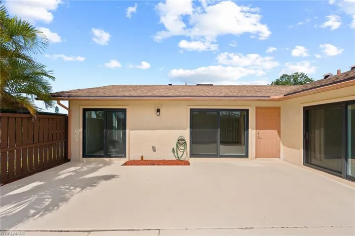 Rear view of house with a patio area, stucco siding, and fence