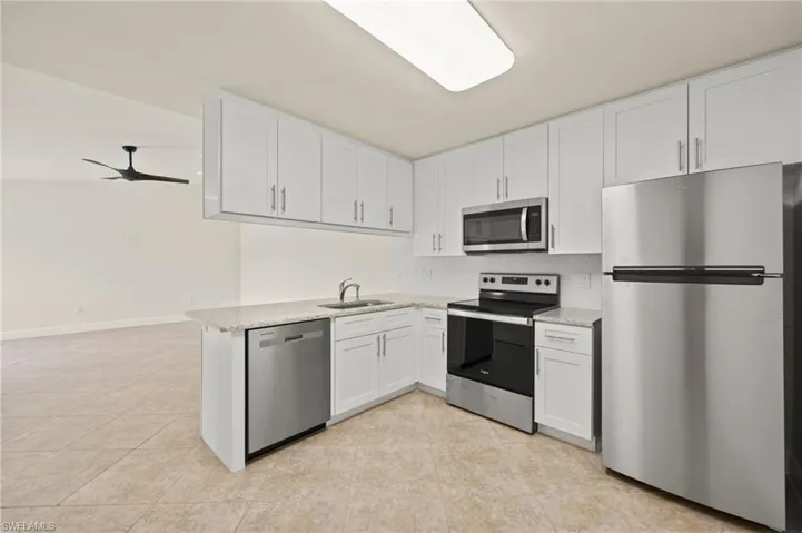 Kitchen featuring appliances with stainless steel finishes, white cabinets, tasteful backsplash, and a sink