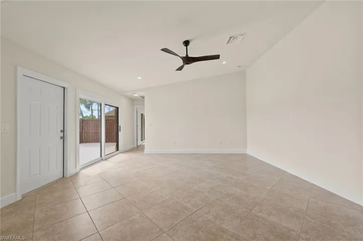 Empty room featuring a ceiling fan, light tile patterned floors, baseboards, recessed lighting, and vaulted ceiling