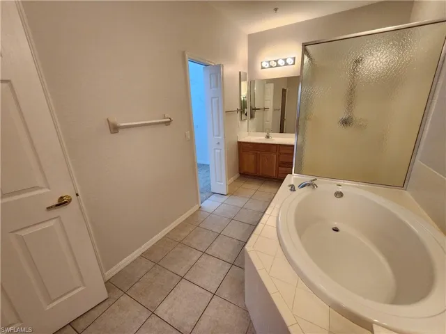 Bathroom with tile patterned flooring, shower with separate bathtub, and vanity