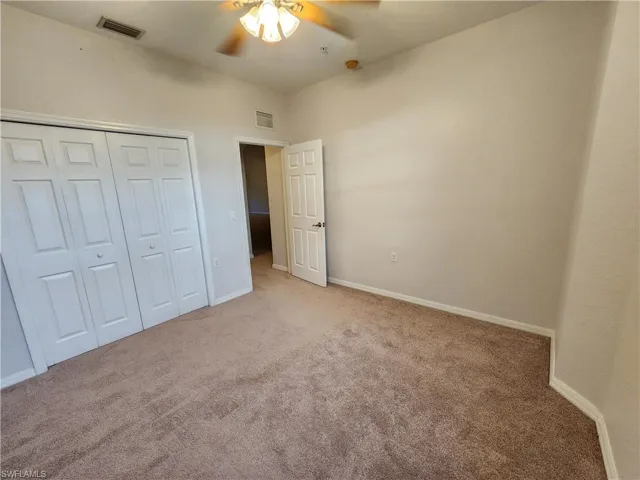 Unfurnished bedroom featuring a closet, light carpet, and ceiling fan