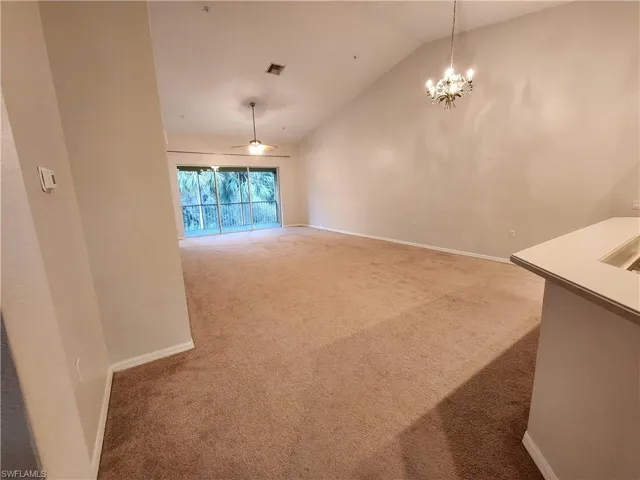 Unfurnished dining area with an inviting chandelier, vaulted ceiling, and carpet flooring