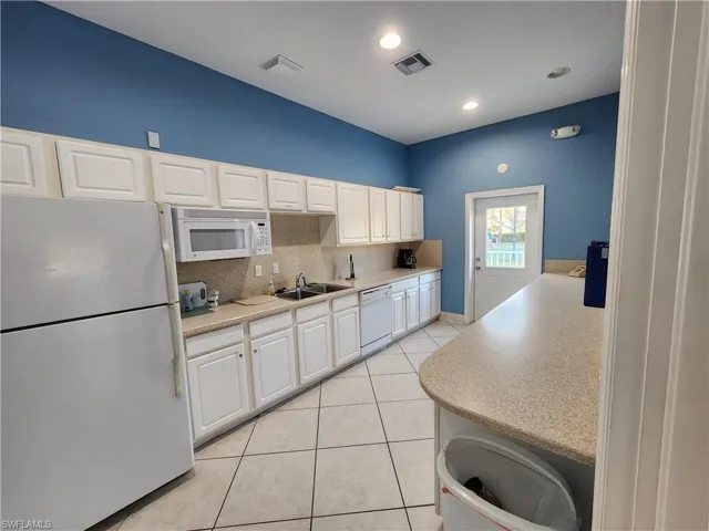 Kitchen featuring white appliances, tasteful backsplash, white cabinetry, light tile patterned flooring, and recessed lighting