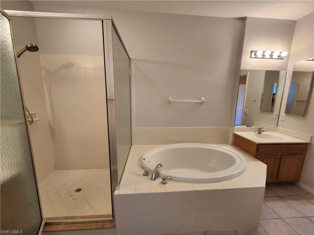 Bathroom featuring vanity, independent shower and bath, and tile patterned floors