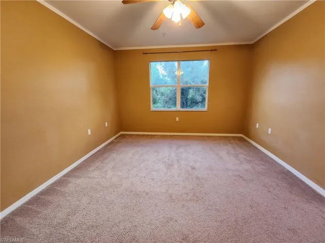Unfurnished room featuring ornamental molding, carpet flooring, and ceiling fan