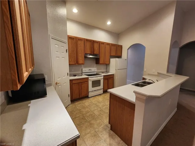 Kitchen with kitchen peninsula, sink, and white appliances