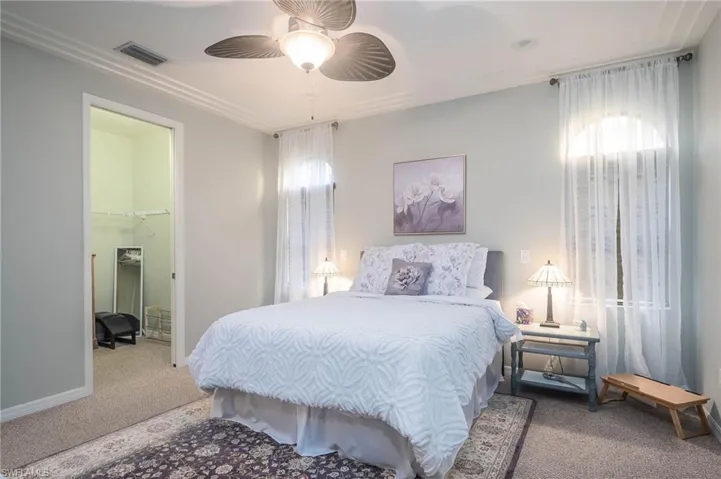 Carpeted master bedroom with a walk in closet, a closet, and ceiling fan