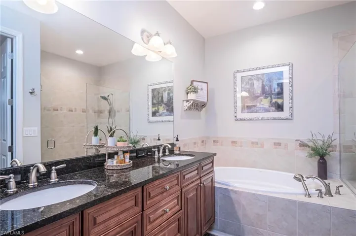 Bathroom featuring duual vanities, tub  and walk in shower