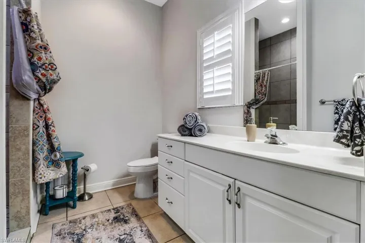 Bathroom featuring tile patterned floors, a tile shower, and vanity