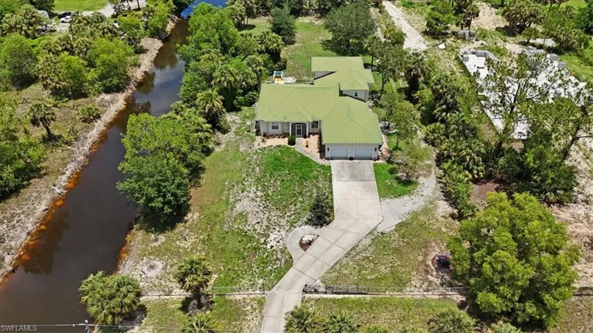 View from above of property with a tree filled landscape and a nearby body of water