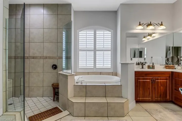 Full bath with a bath, vanity, tile patterned floors, and walk in shower