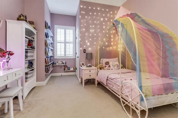 Bedroom featuring light carpet and baseboards