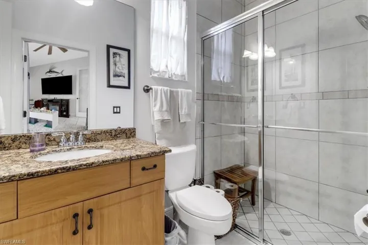 Bathroom featuring vanity, a stall shower, and a ceiling fan